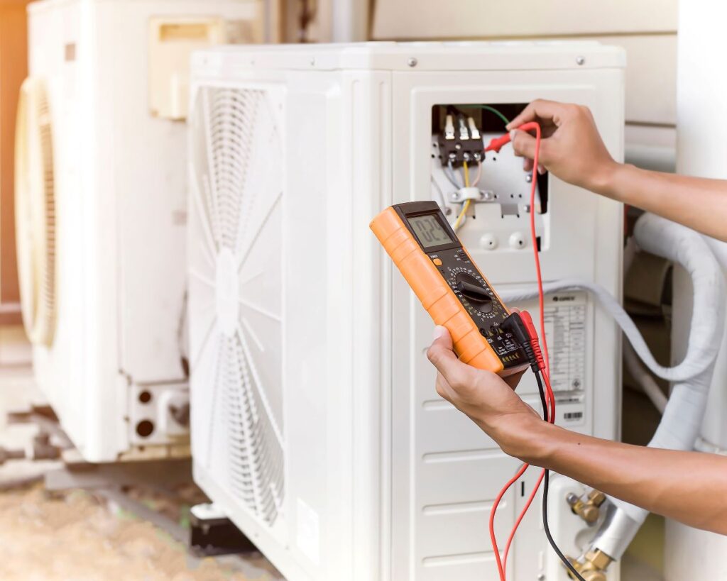 Technician using a multimeter to test electrical connections on an HVAC unit