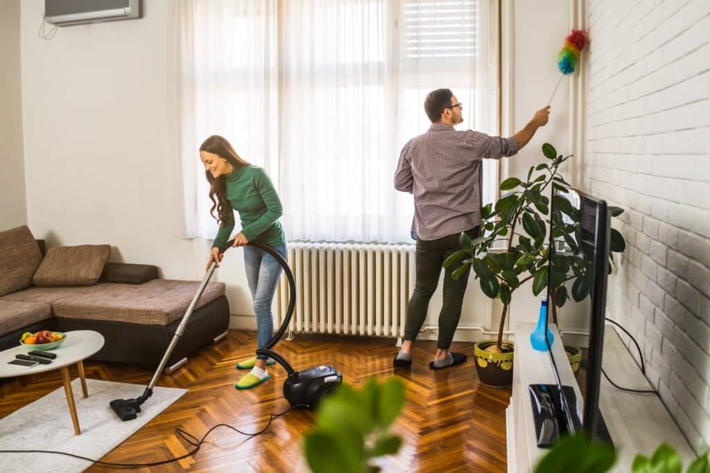 Paar reinigt mit Hyla Staubsauger das Wohnzimmer