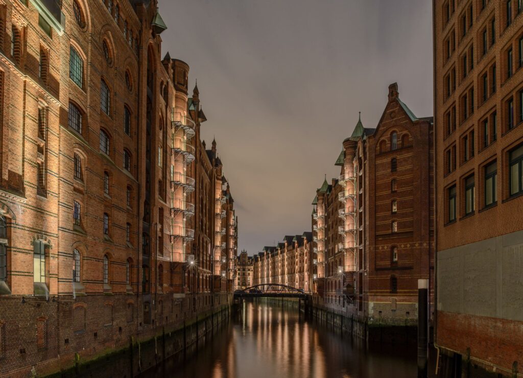 Beleuchtete Speicherstadt in Hamburg bei Nacht mit spiegelndem Wasser zwischen historischen Backsteingebäuden