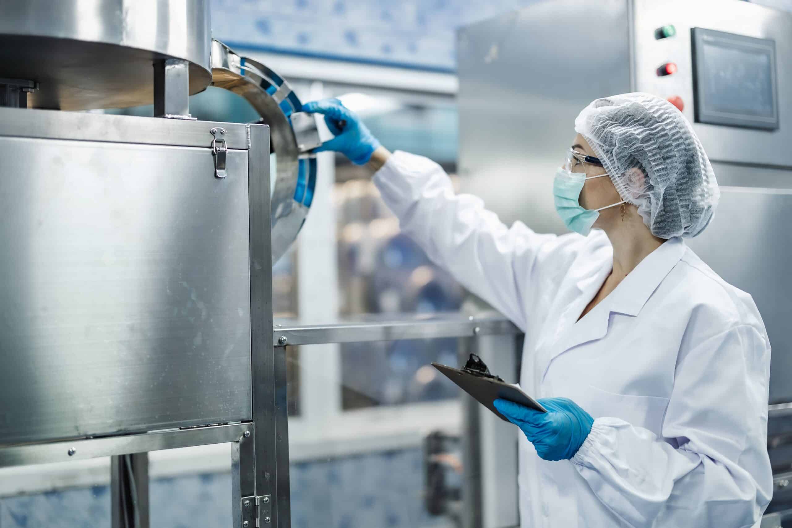 Technikerin im Reinraum prüft eine Industrieanlage mit Klemmbrett