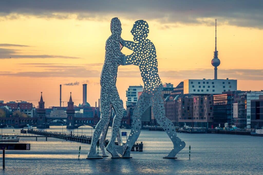 Skulptur Molecule Man in Berlin bei Sonnenuntergang mit Fernsehturm im Hintergrund – Symbol fuer kulturelle Vielfalt rund um internationale Privatschule Berlin