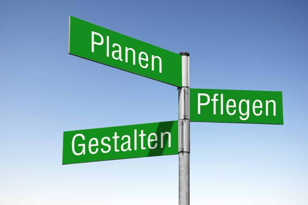 Wegweiser mit den Begriffen Planen, Pflegen und Gestalten im Garten | Travertin